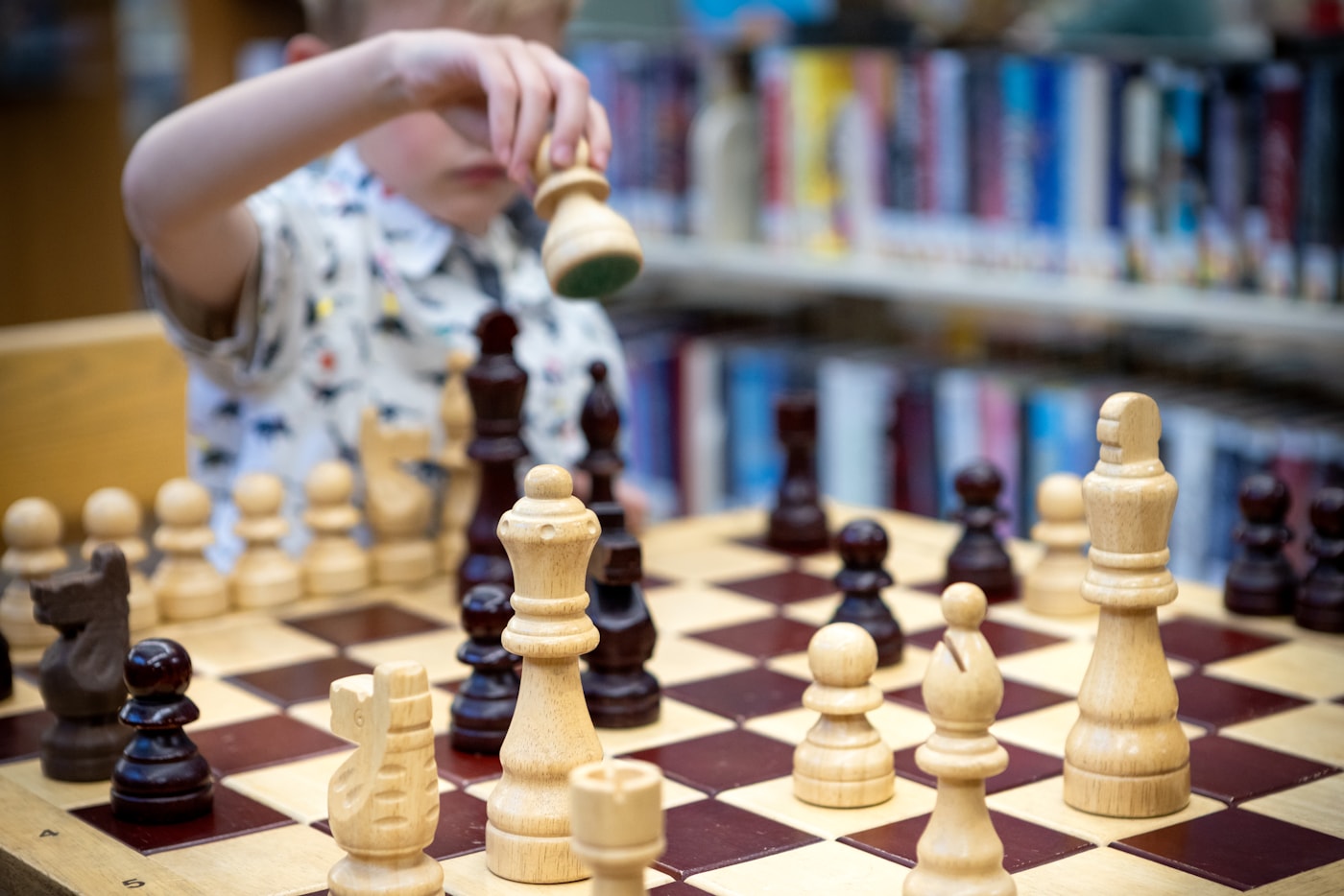 A young student moves a chess piece during a game at a public library